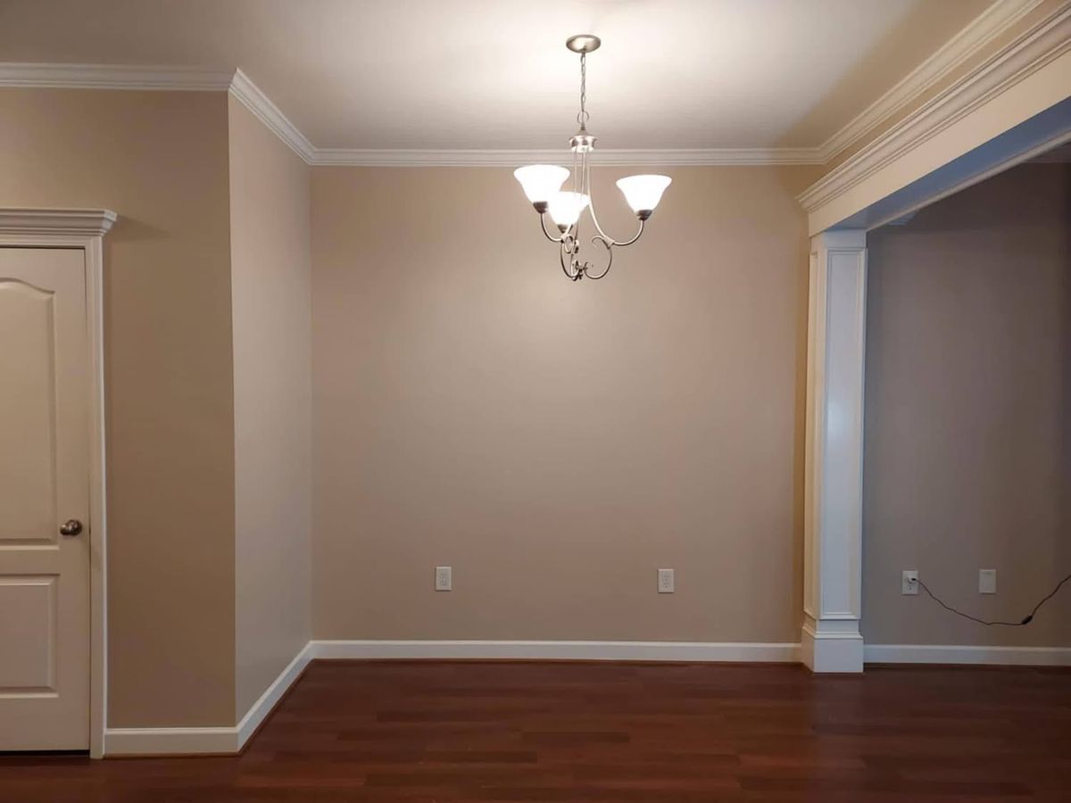 Dining room with beige walls, white crown molding, white columns and a chandelier