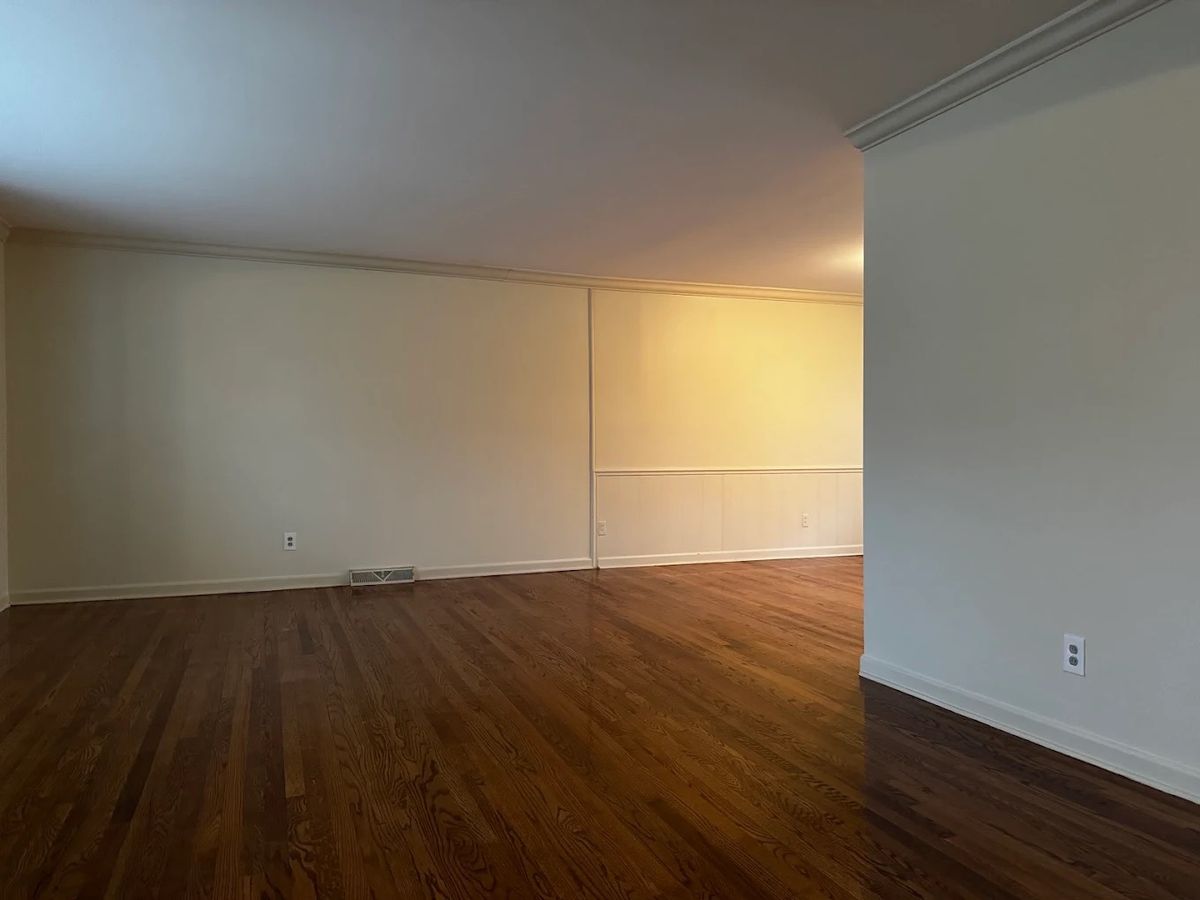 Long open room with freshly painted white walls, ceiling and crown molding over wood floors